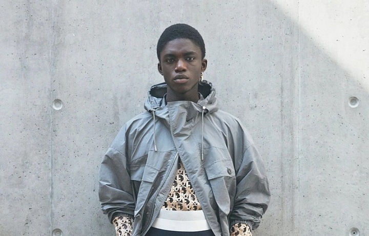 Muž v béžových kalhotách a šedé bundě Dior