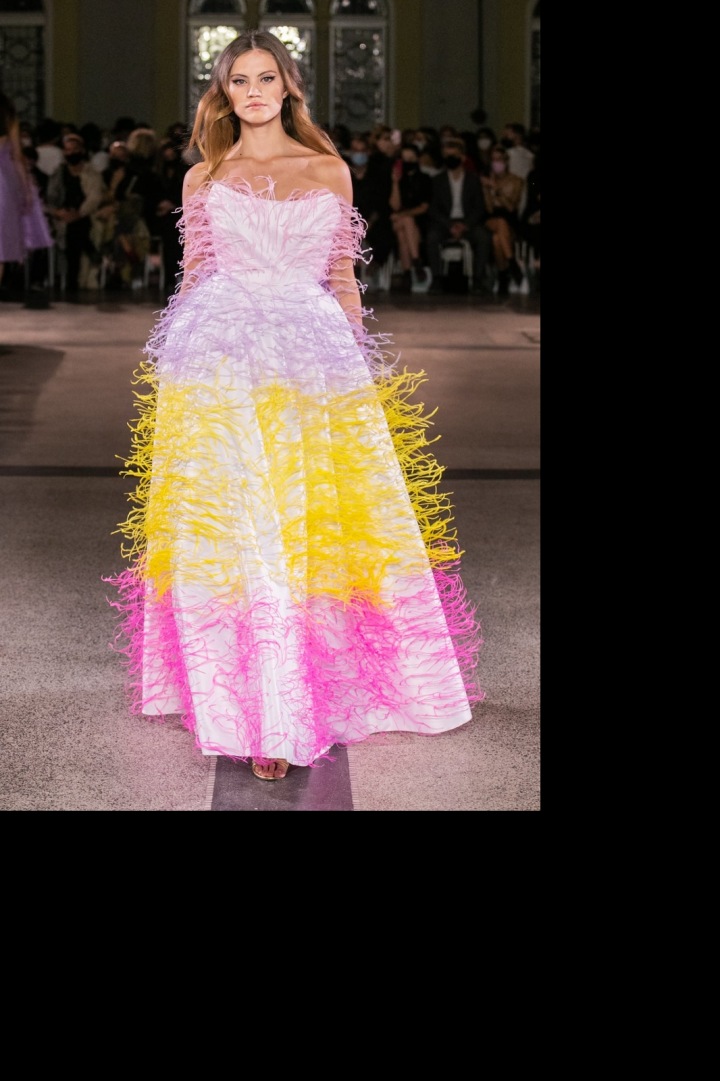 Modelka má na sobě dlouhé šaty pošité pírky od Vandy Jandy