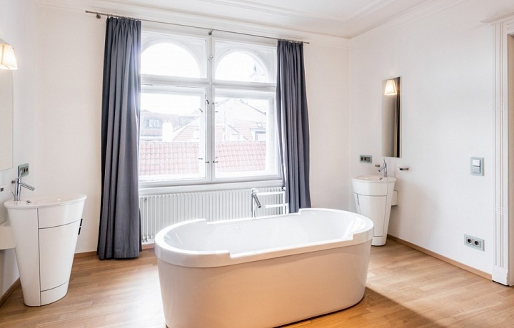 Prostorná ložnice s vanou v prostoru a výhledem na Prahu