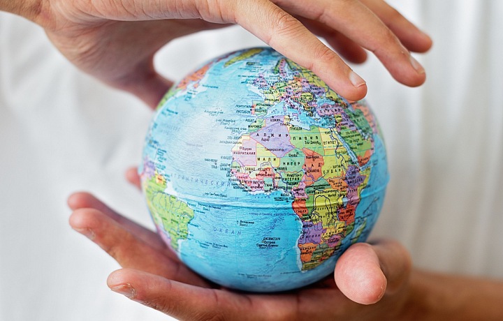 Hands holding a small globe.